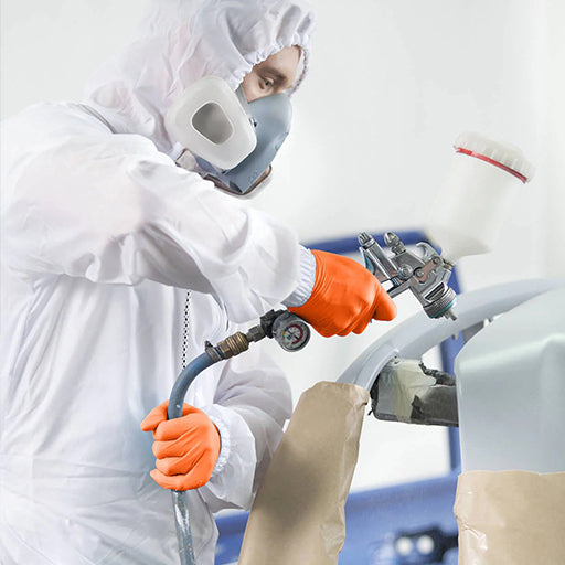 Man with a spray gun painting wearing orange nitrile gloves